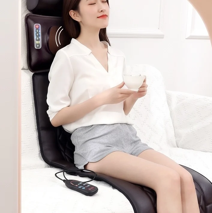 Person seated upright on the massage mattress holding a cup