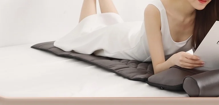 Person lying face down on the massage mattress reading